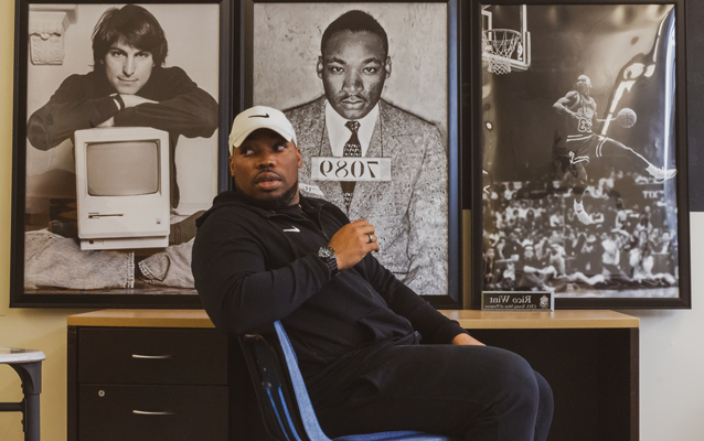 Rico Wint sits in front of large framed photos of Michael Jordan, Martin Luther King Jr.史蒂夫·乔布斯