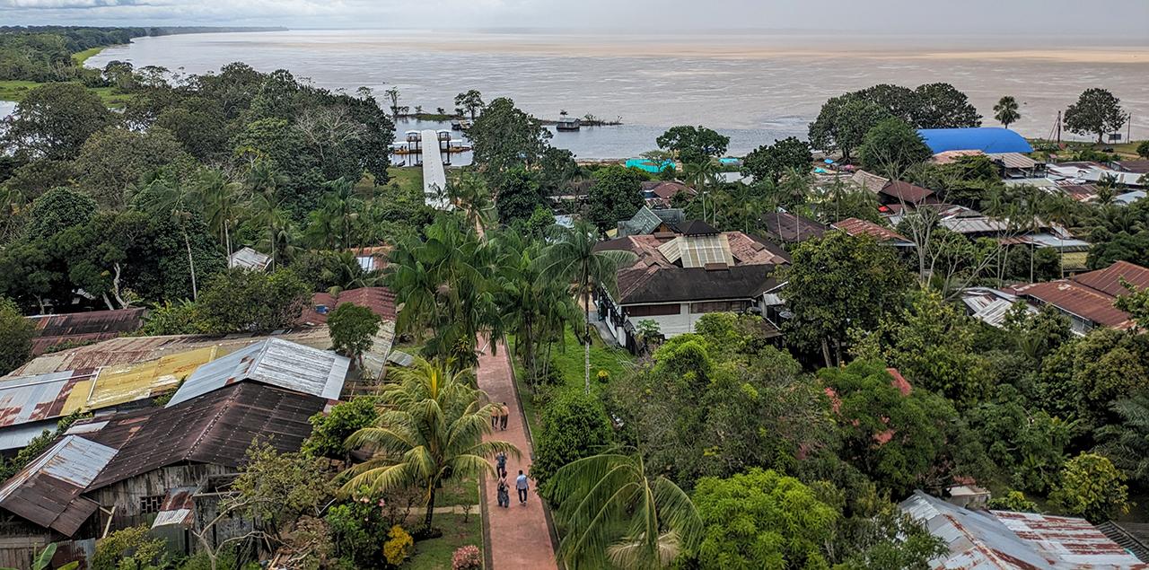 A view of the banks of the Amazon River from a town in Colombia surrounded in green trees.