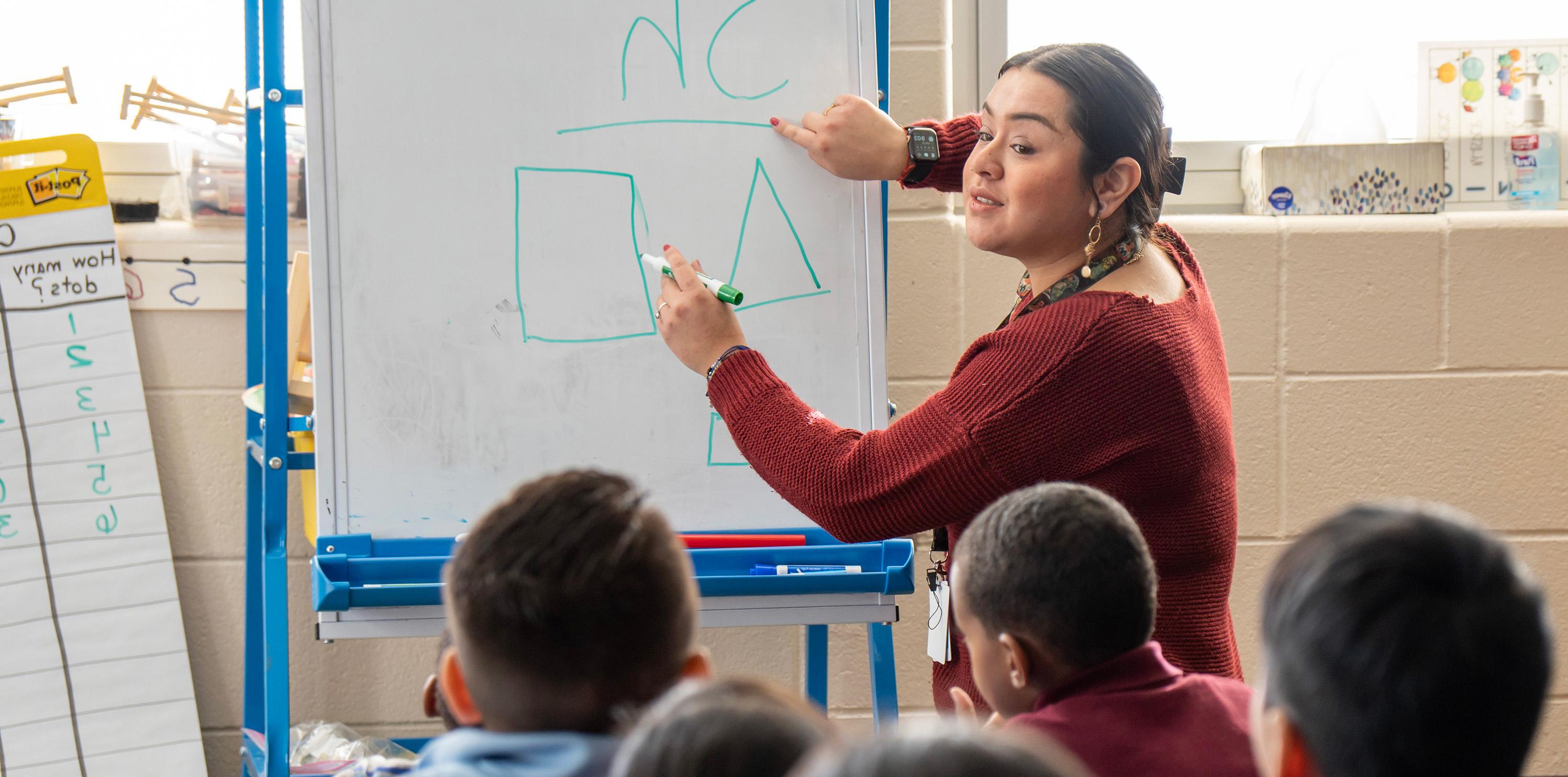 Teacher pointing at shapes in front of young students