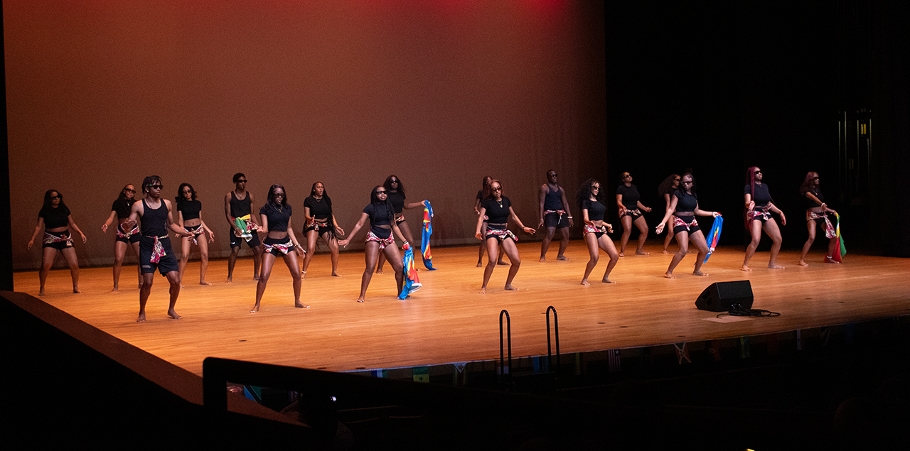 Men and women wearing black dancing in unison on a stage